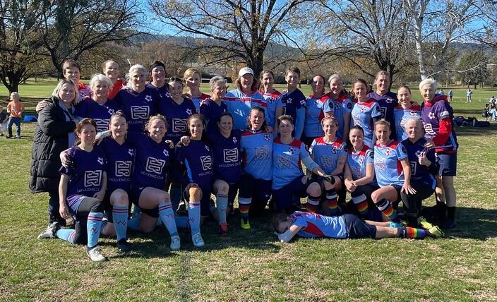 Group photo of two women's soccer teams, one in a purple jersey while the other in blue.
